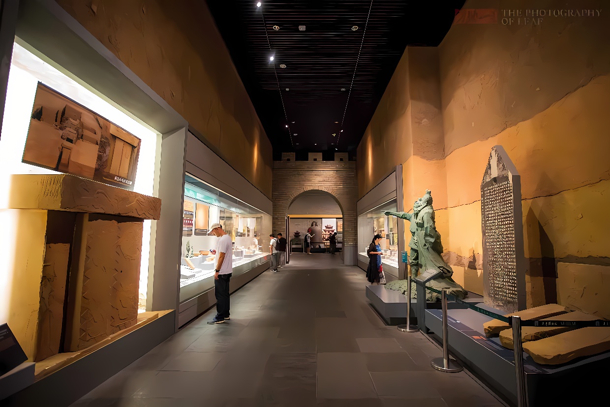 图片展示了一个博物馆内部，墙上挂有艺术品，中间放置雕塑，参观者在安静地观赏展出的文物。