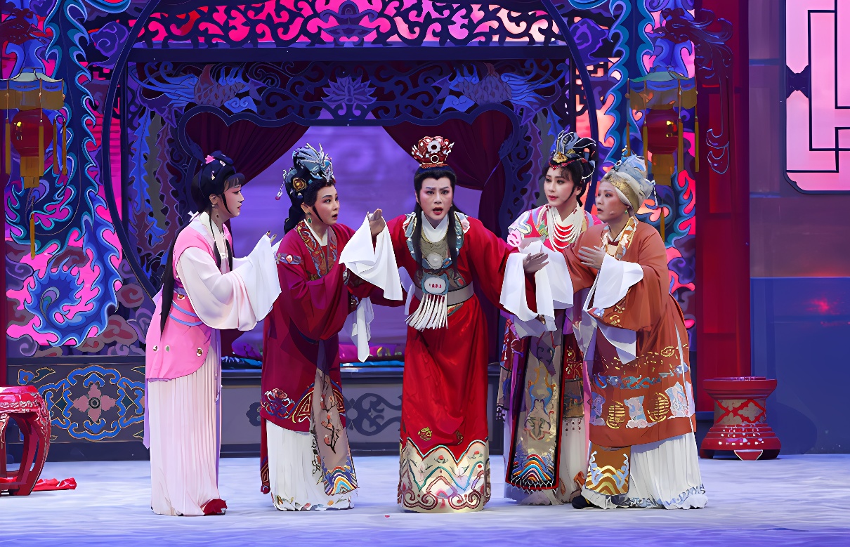 图中展示了五位身着传统服饰的演员在舞台上表演，背景是中国风格的建筑，氛围庄重，色彩丰富。