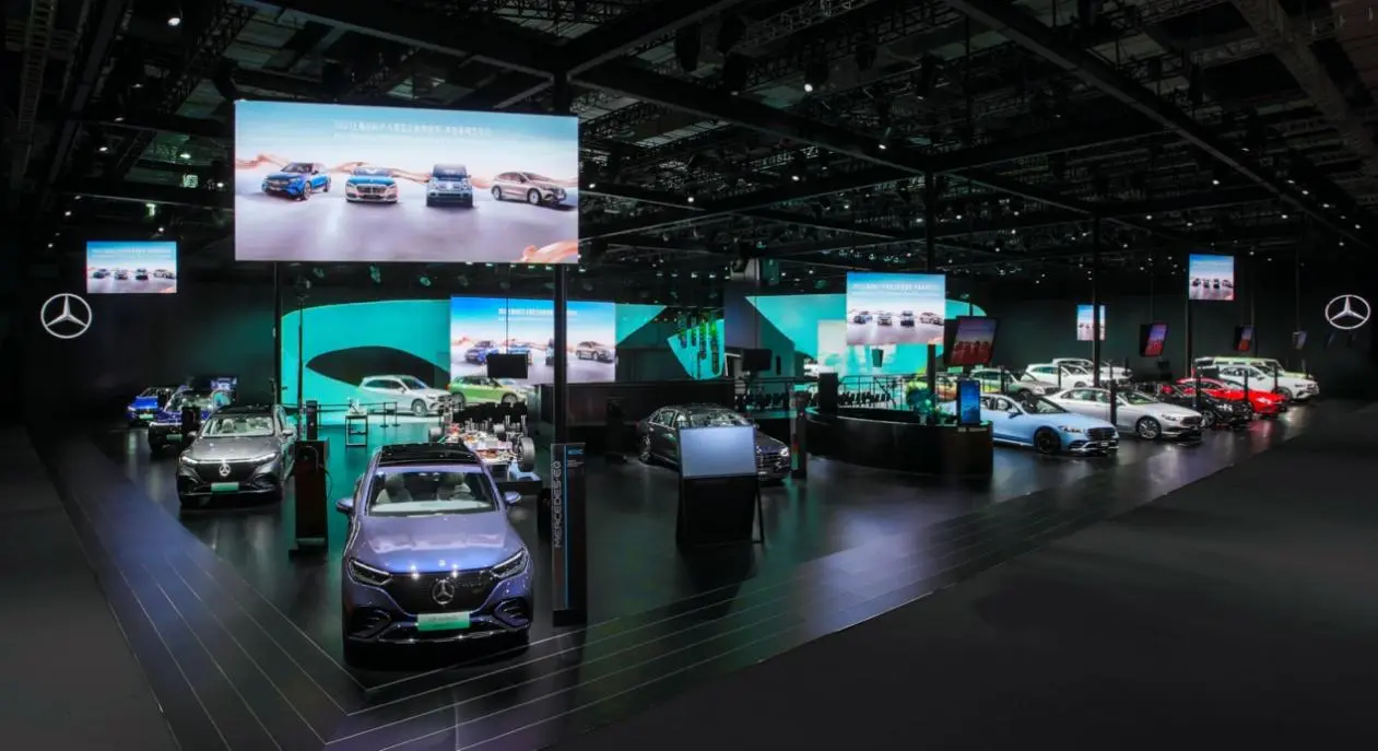 这是一张车展的照片，展示了多款汽车，包括经典和现代车型。展厅内灯光昏暗，布局精致，氛围专业。