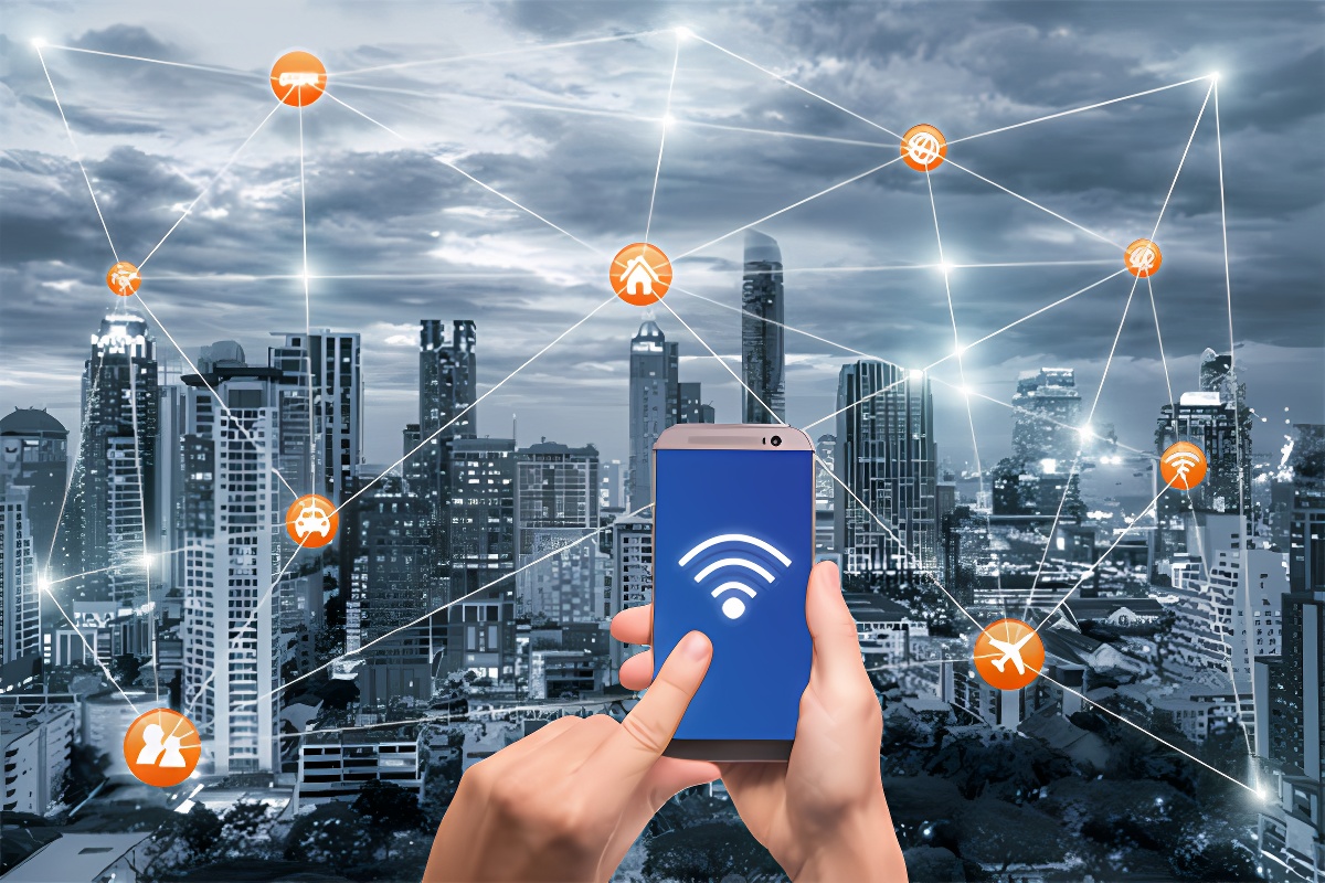 图片展示双手持手机，屏幕显示Wi-Fi信号，背景是高楼大厦的城市夜景，象征网络连接，城市中出现多个互联网相关的图标和连线。