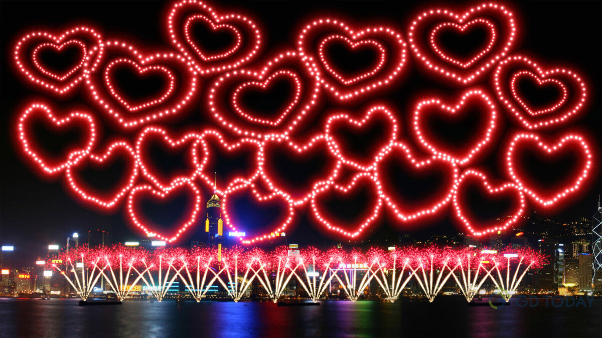 图片展示了夜晚璀璨的城市天际线背景下，由无数红色心形组成的壮观烟花表演，显得浪漫而壮丽。