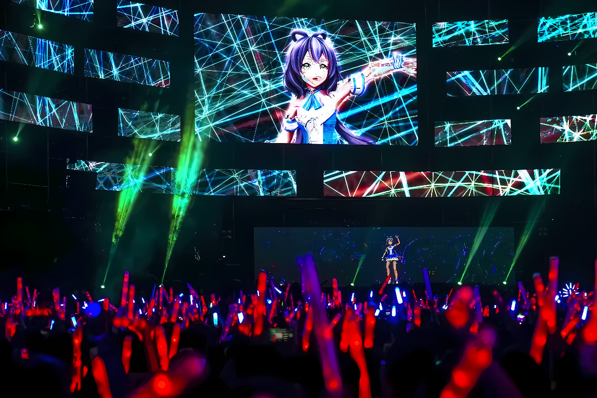 图片展示了一场虚拟偶像演唱会，舞台上有大型屏幕，观众手持荧光棒，在光影中享受音乐和表演。