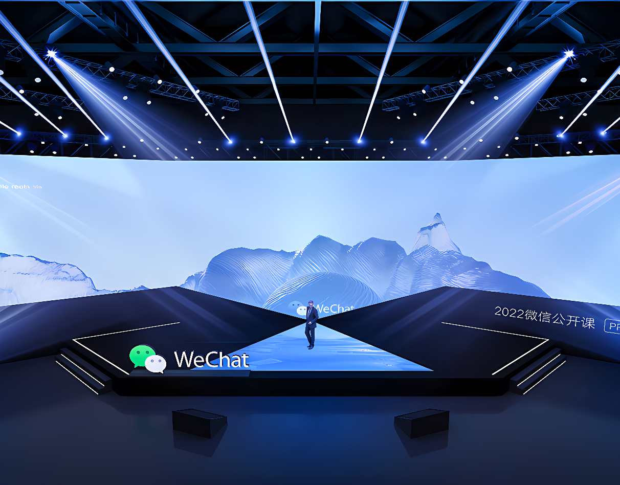 图片展示了一个现代化的演讲舞台，舞台背景是山脉图案，中间有一人站立，下方显示着“WeChat”字样和日期。舞台灯光照亮着场地。