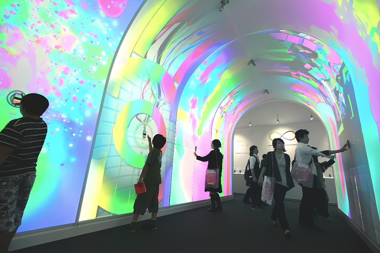 这是一张展示现代艺术展览的照片，人们在五彩斑斓、光影变幻的走廊中参观，显得好奇和兴奋。