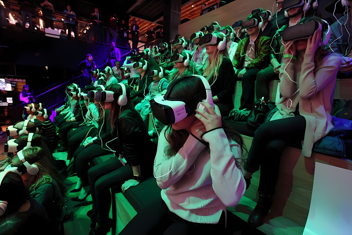 图片展示了一群人坐在观众席上，他们戴着虚拟现实头盔，似乎正在体验某种沉浸式的虚拟现实内容。