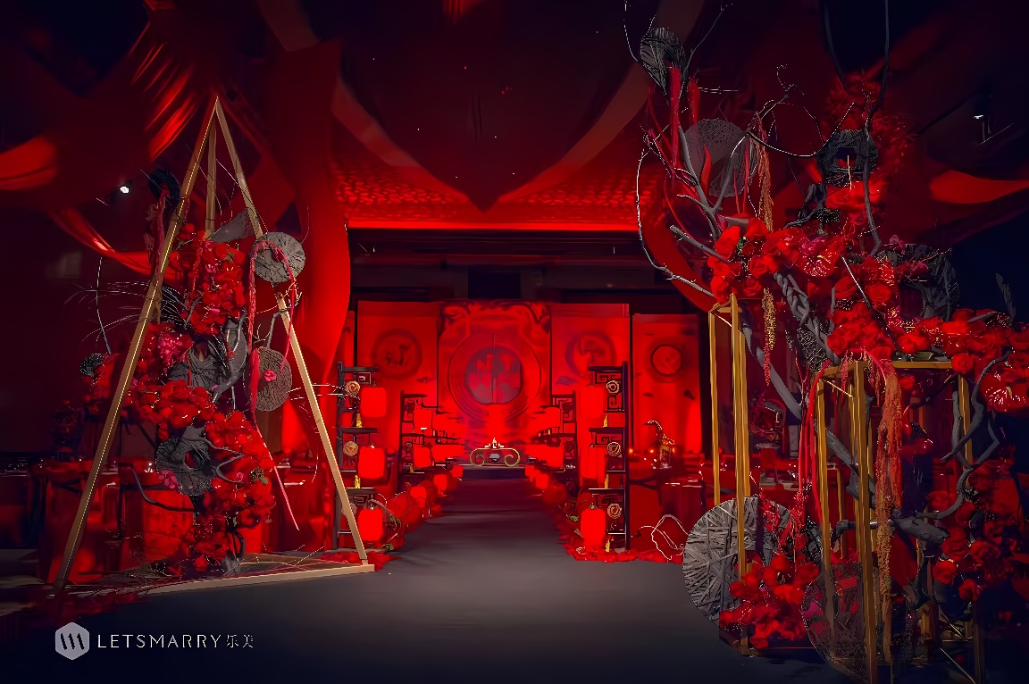 这是一张婚礼现场的照片，以红色为主题，装饰华丽，有花环和灯笼，氛围喜庆，场地布置得十分精致而富有中国传统风格。