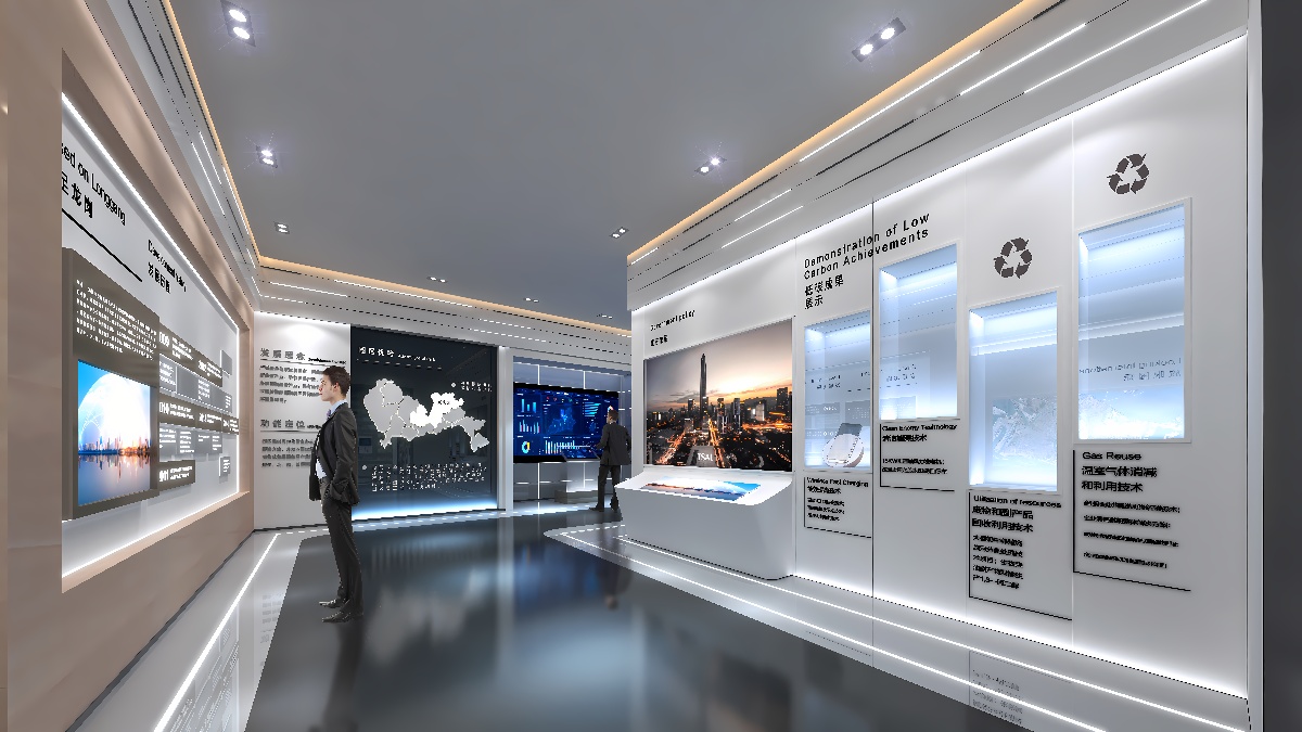 这是一张现代展览厅内部的照片，有人在观看墙面展示的信息，展厅设计简洁，以白色和灰色为主调，光线明亮。