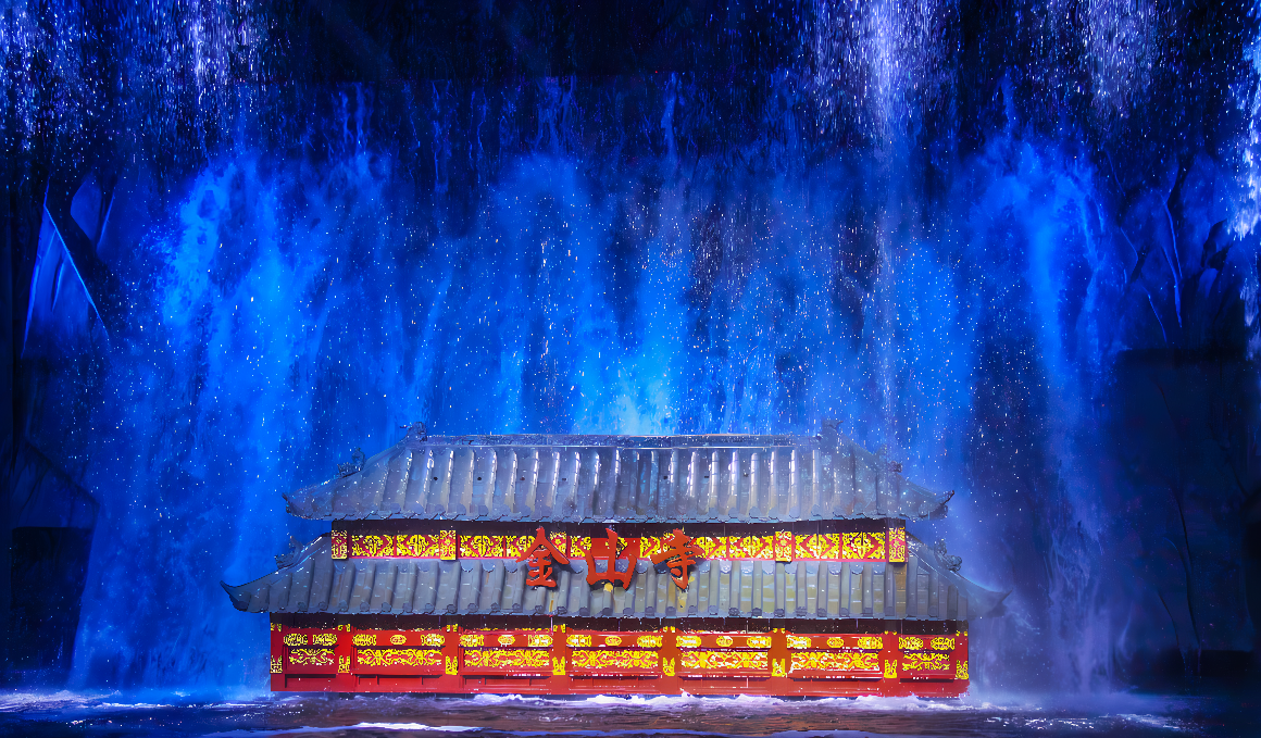 图片展示了一座亮丽多彩的亭子，背后是壮观的瀑布，四周似乎有灯光效果，营造出梦幻般的氛围。