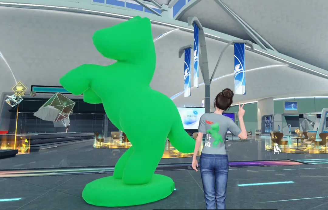 图片展示了一位穿着印有图案T恤的人站在一个现代化室内空间，正拍摄一个巨大的绿色雕塑。