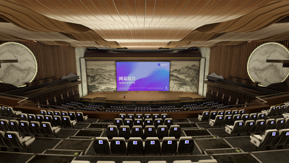 这是一个现代化的演讲厅，有排列整齐的座椅，舞台上有演讲者，背景是大屏幕，两侧装饰有石雕。