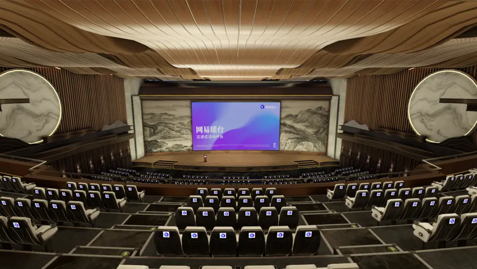 图片展示了一位演讲者站在现代化演讲厅的舞台上，背景是大屏幕，厅内布置有整齐的座椅，装饰豪华。