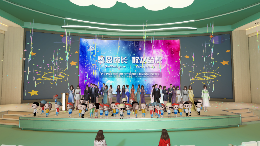 图片展示了一场表演，台上有多位穿着正式服装的人和一排卡通人物模型，背景是带有星空和文字的横幅。