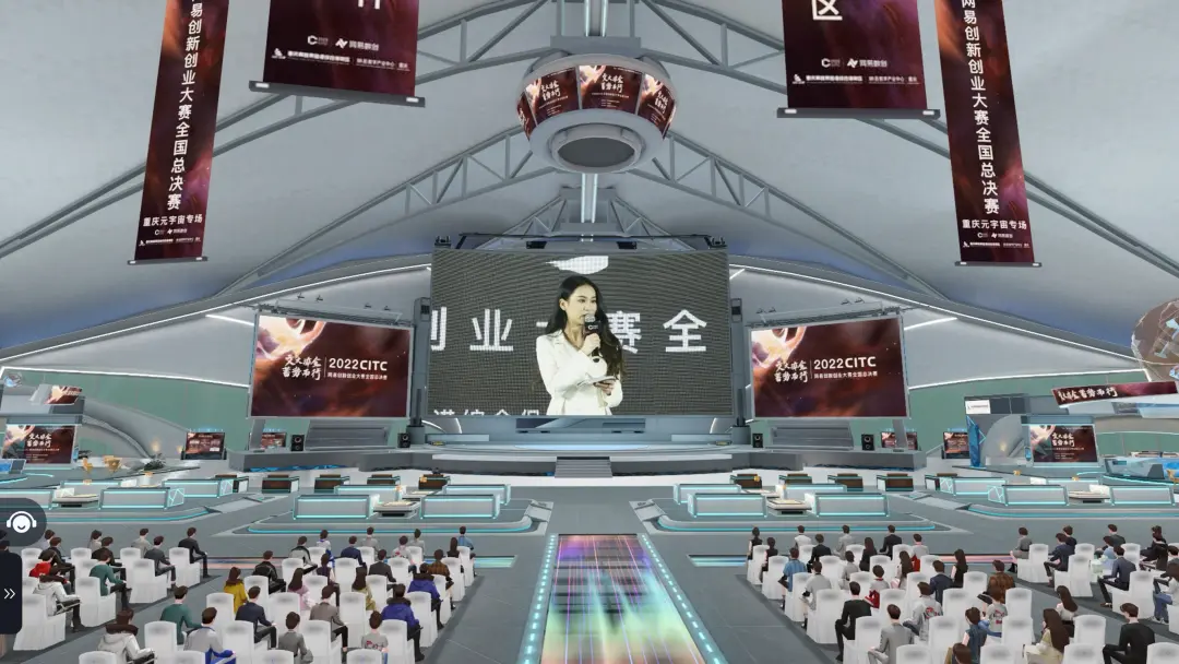 图片展示了一个现代化的室内场馆，中央有大屏幕播放着演讲者的影像，周围坐满了观众，环境科技感十足。