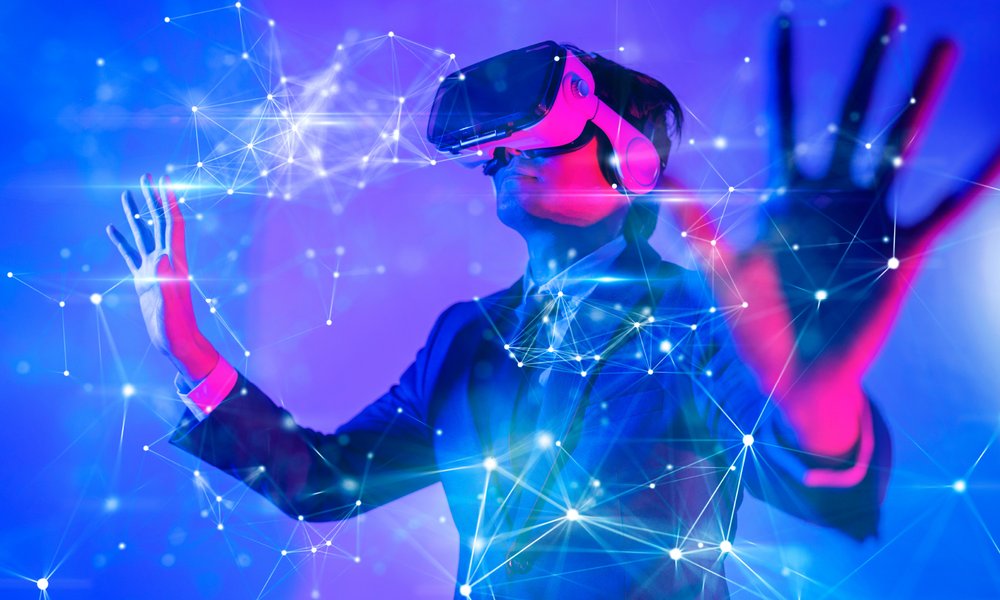 图片展示一位佩戴虚拟现实头盔的人，伸手触摸虚构的三维数字界面，周围光线斑斓，科技感十足。