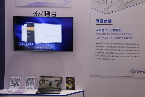 图片展示了一个信息化展台，有电视屏幕、笔记本电脑和介绍文字，墙上有二维码和公司标识，场景像是在一个展览会。