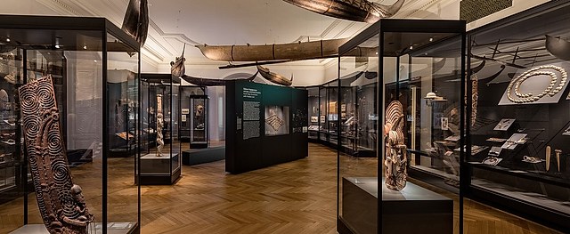 图片展示了一个博物馆内部，陈列着多个展示柜，里面摆放着各种艺术品和文物，墙面上有解释性文字。