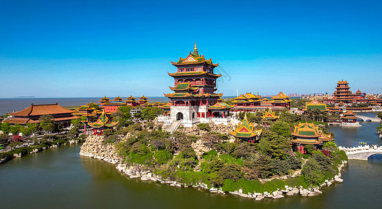 这是一张展示中国传统宫殿建筑的照片，建筑群坐落在水中的岛上，颜色鲜艳，风格古典，周围环境优美，天空晴朗。