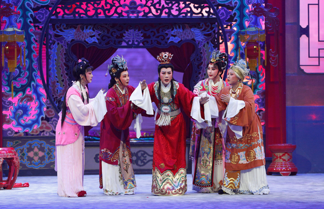 图片展示了五位身着传统服饰的演员，正站在装饰华丽的舞台上，似乎正在表演一个中国古典戏剧。