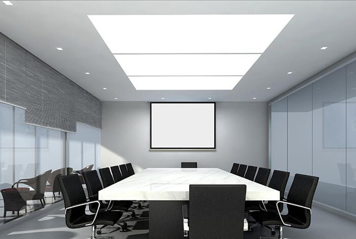 图片展示了一个现代风格的会议室，中间有一张长会议桌，周围摆放着多把黑色办公椅，墙上挂着一块空白的展示屏。