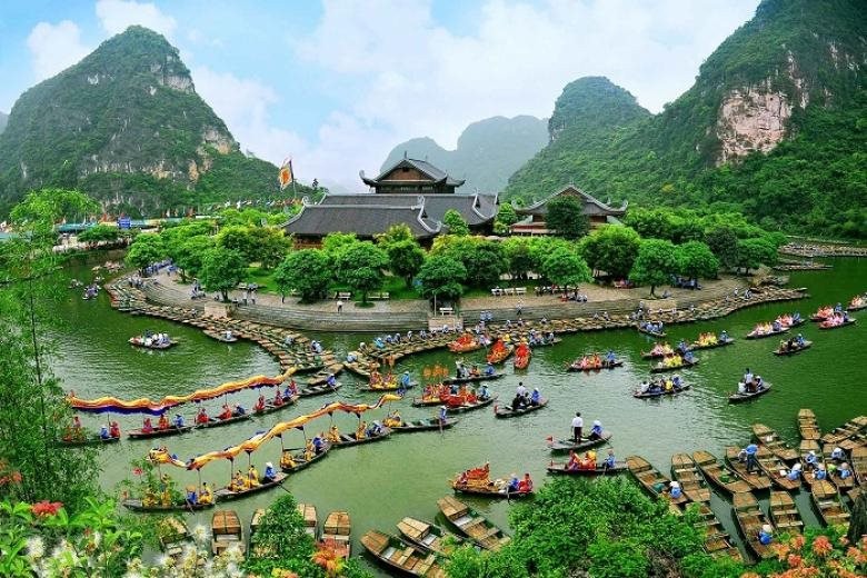 图片展示了一处风景如画的山水园林，游客在碧水中划船，周围是青山和亭台楼阁，景色宁静而美丽。