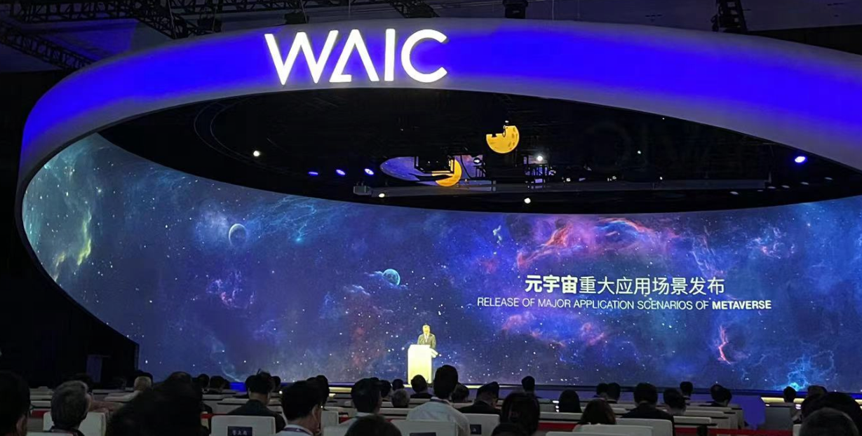 图片展示了一个科技会议现场，舞台背景有宇宙星空图案，台上有演讲者，台下观众认真聆听。