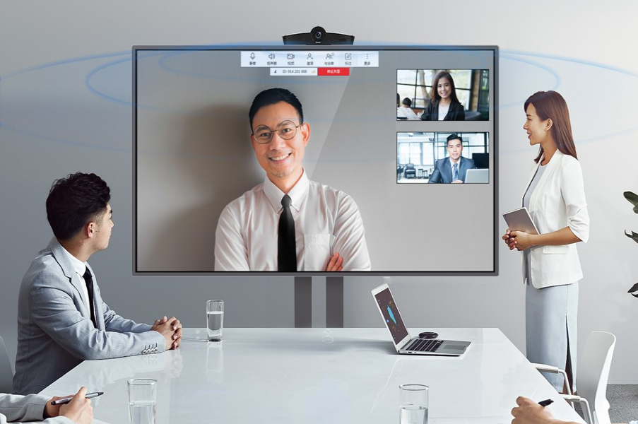 图片展示了一场视频会议，三位参与者通过大屏幕交流，其中两位在会议室，一位通过远程视频加入。