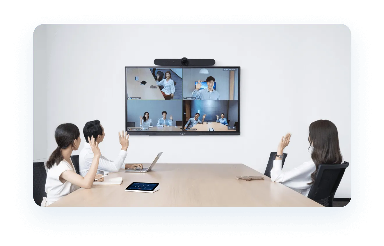 图片展示了一场视频会议，三位女性坐在会议室内，屏幕上显示远程参会者，环境看起来专业且现代化。