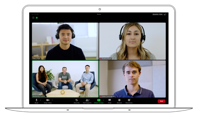 笔记本电脑屏幕显示Zoom视频会议界面，四个窗口分别有四位参与者，各自位于不同的环境中进行远程交流。