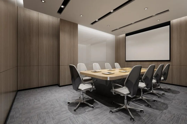 这是一个现代会议室，配有长会议桌、多把办公椅，墙上安装有投影屏幕，房间设计简洁，以木质和中性色调为主。