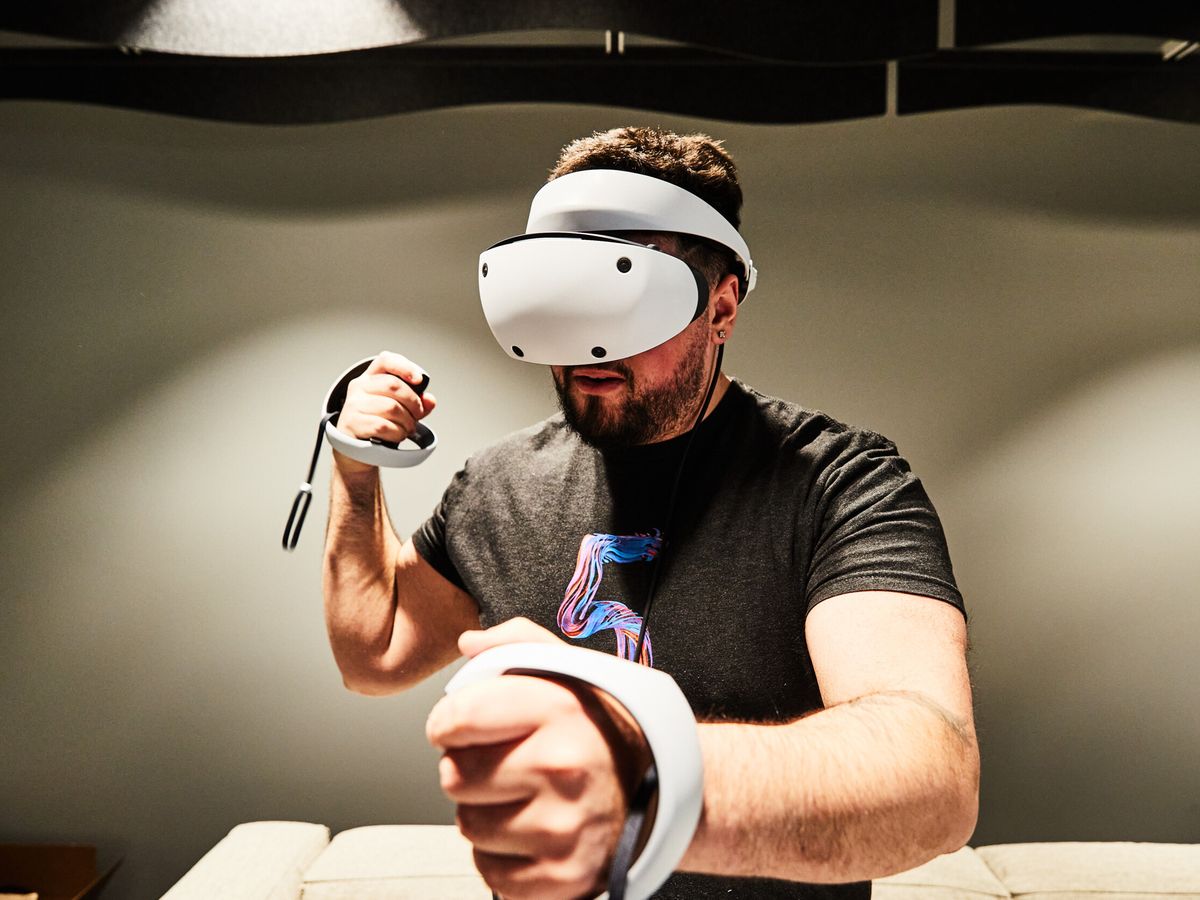 图片中是一位男士戴着虚拟现实头盔，正专注地使用手中的控制器，似乎在体验虚拟现实游戏。他穿着黑色短袖。