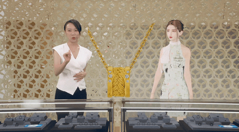 图片展示一位女士站在柜台前，介绍产品。背景有一个挂着金色链条包的立体模型和一位穿旗袍的女性模型。