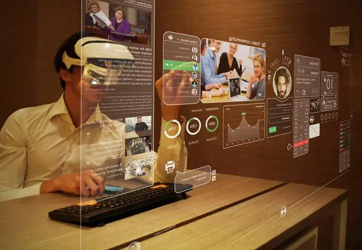图片展示一位佩戴头戴式设备的人在操作虚拟显示屏，周围充满了未来科技感的图形和数据界面。