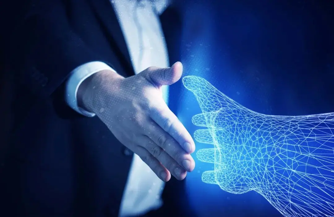 图片展示了一位穿着正装的人与一只蓝色数字化图形手握手的场景，象征着人类与科技之间的互动与融合。