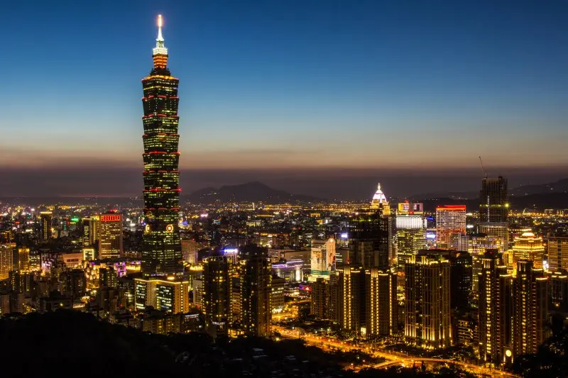这是一张城市夜景照片，显示了繁华的都市灯光，高楼大厦中央耸立一栋特别高的摩天大楼，天空呈现晚霞余晖。