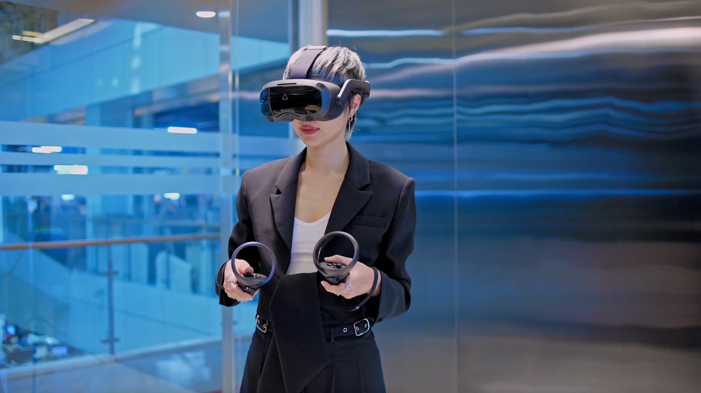图片展示一位女士穿着商务装，戴着虚拟现实头盔和手持控制器，站在现代化办公室内，似乎正在体验VR技术。