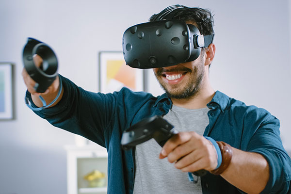 图片展示一位男士戴着虚拟现实头盔，正使用手持控制器进行互动，看上去沉浸在虚拟世界的体验中。