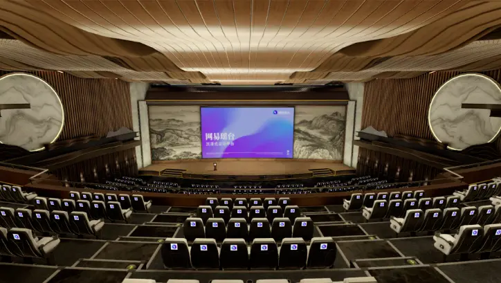 这是一个现代会议厅内部的图片，配有宽敞的座位区、一个大舞台和两侧的装饰壁画。舞台上有屏幕和一位演讲者。