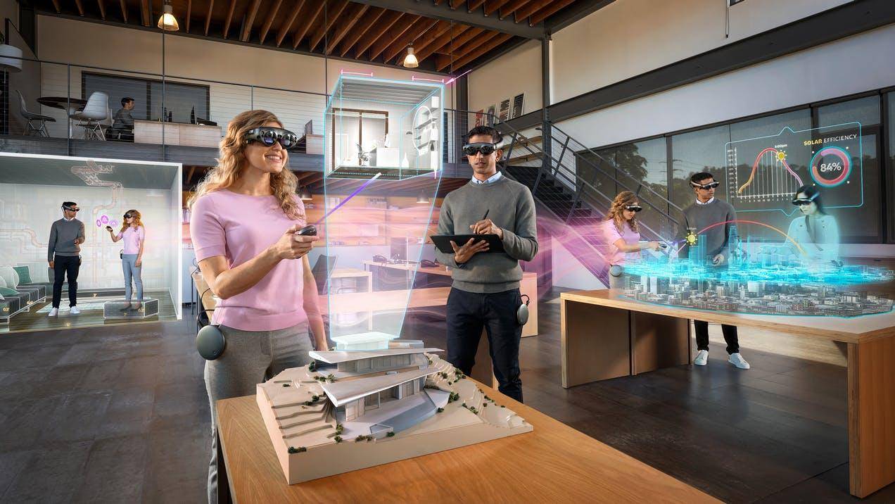 图片展示几人戴着增强现实眼镜，围绕模型操作虚拟界面，体验高科技互动，背景是现代化办公空间。