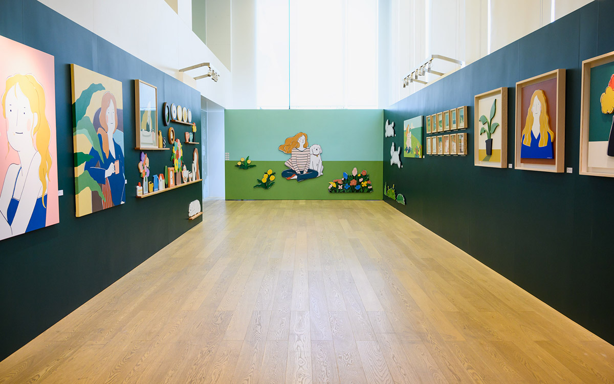 这是一间宽敞明亮的画廊，墙壁挂满了各种风格的画作，地板是木质的，整个空间给人一种简洁舒适的感觉。