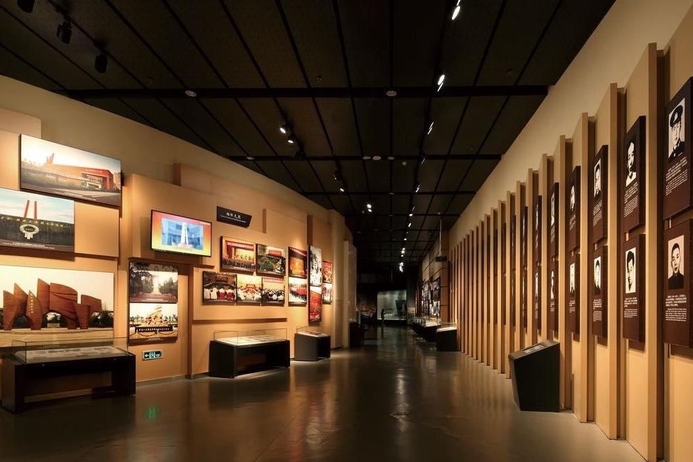 这是一幅展览馆内部的照片，墙壁上挂着各种图片和介绍文字，展厅内部灯光昏暗，氛围庄重，展示着历史或艺术作品。