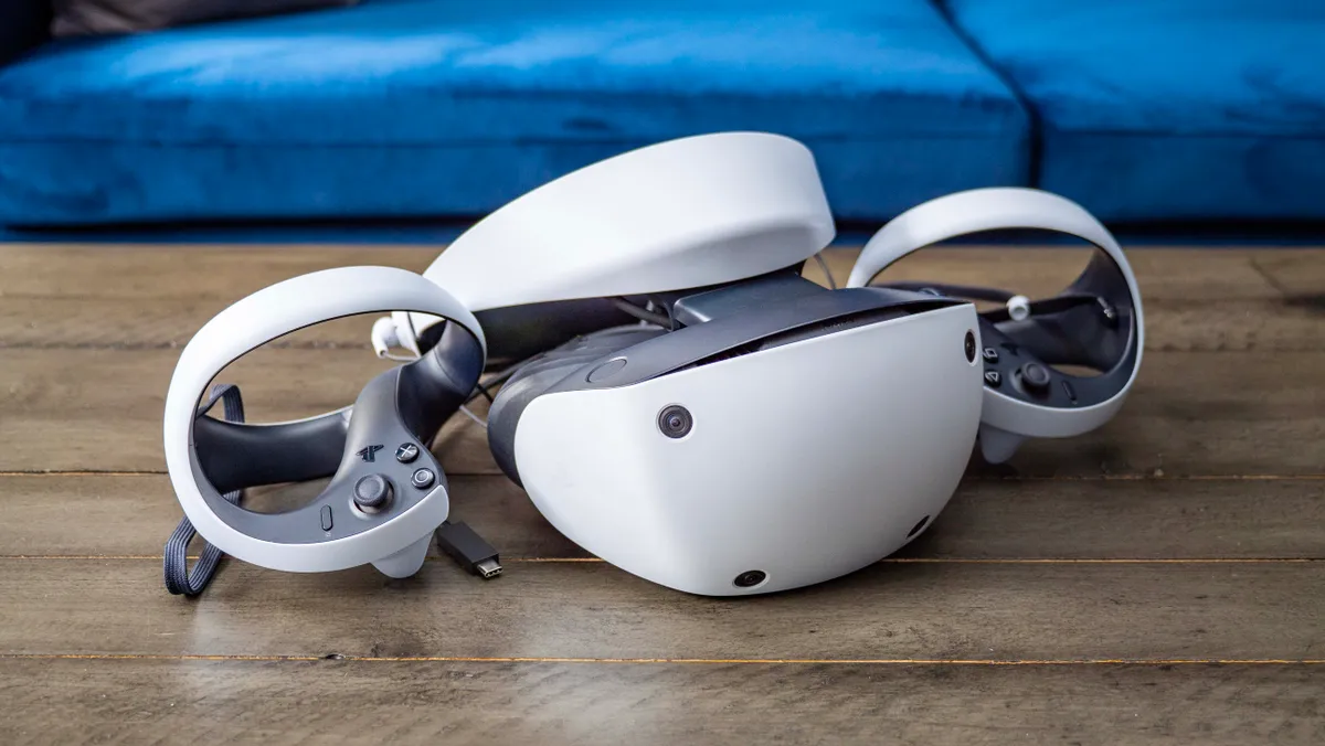 这是一副现代的虚拟现实（VR）头盔和两个手持控制器，放在木地板上，背景是蓝色垫子。