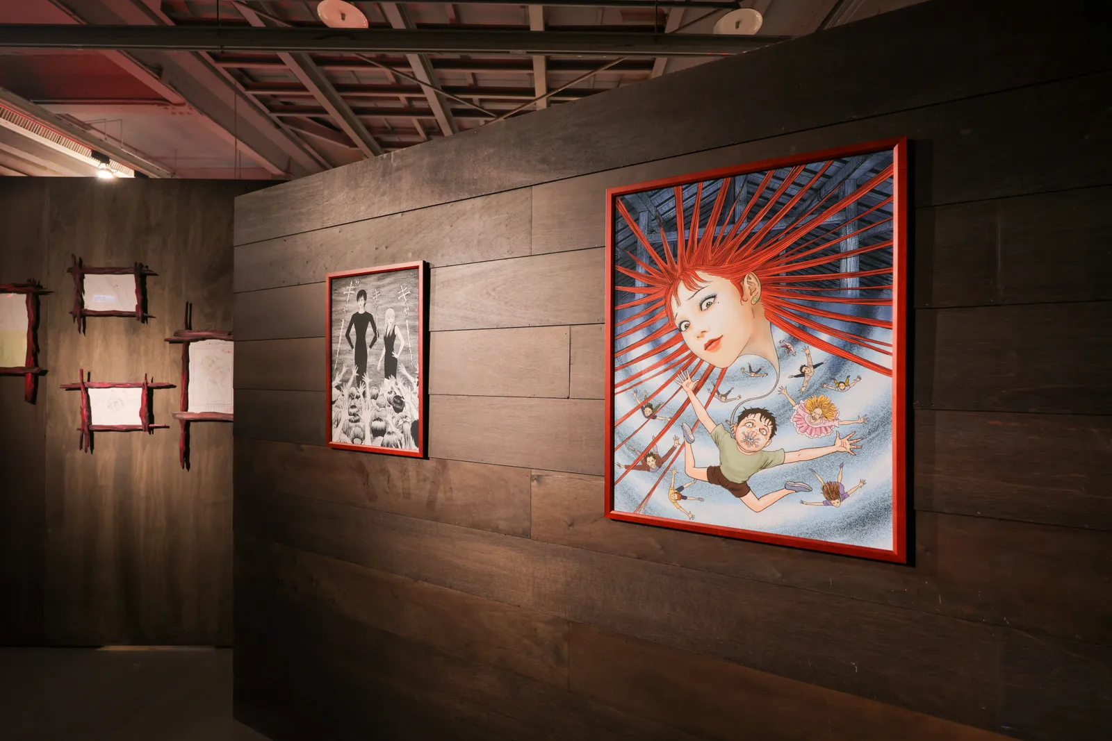 这是一个艺术画廊内部的照片，墙上挂着两幅风格独特的画作，左边的画较小，右边的画色彩鲜艳，主题鲜明。
