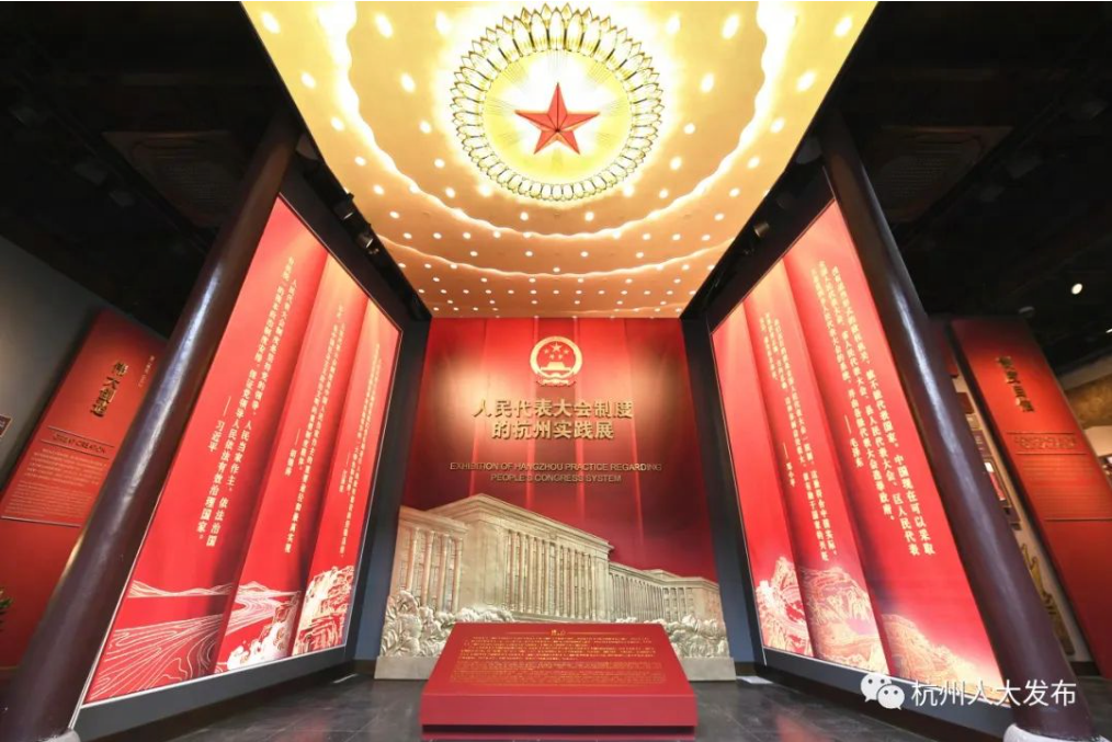 图片展示了一个展览馆内部，中央是一个星形灯饰，两侧墙面上有中文文字和图案，氛围庄严肃穆。