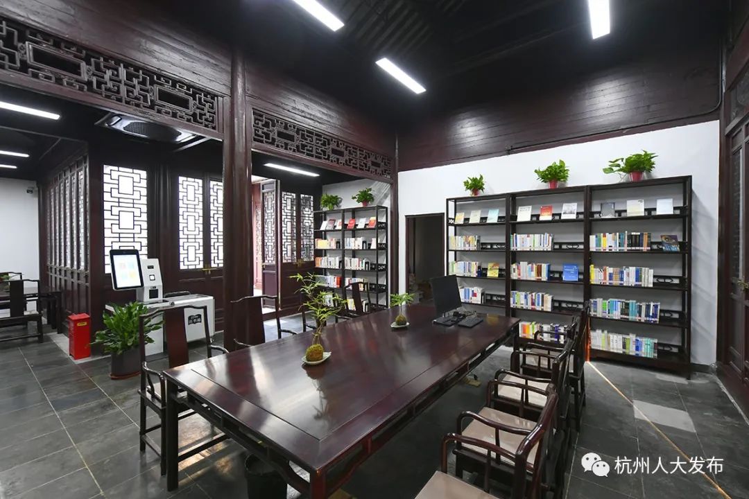 这是一间布局典雅的中式图书馆，内有书架、阅读桌椅和装饰植物，融合了传统木质结构与现代阅读空间的设计。