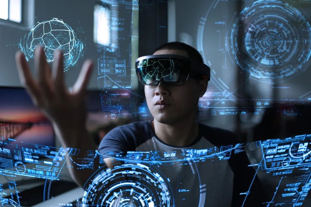 图片展示了一位佩戴先进头戴式显示设备的人，正在用手操作空中的虚拟显示界面，周围充满了科技感的图形和数据。