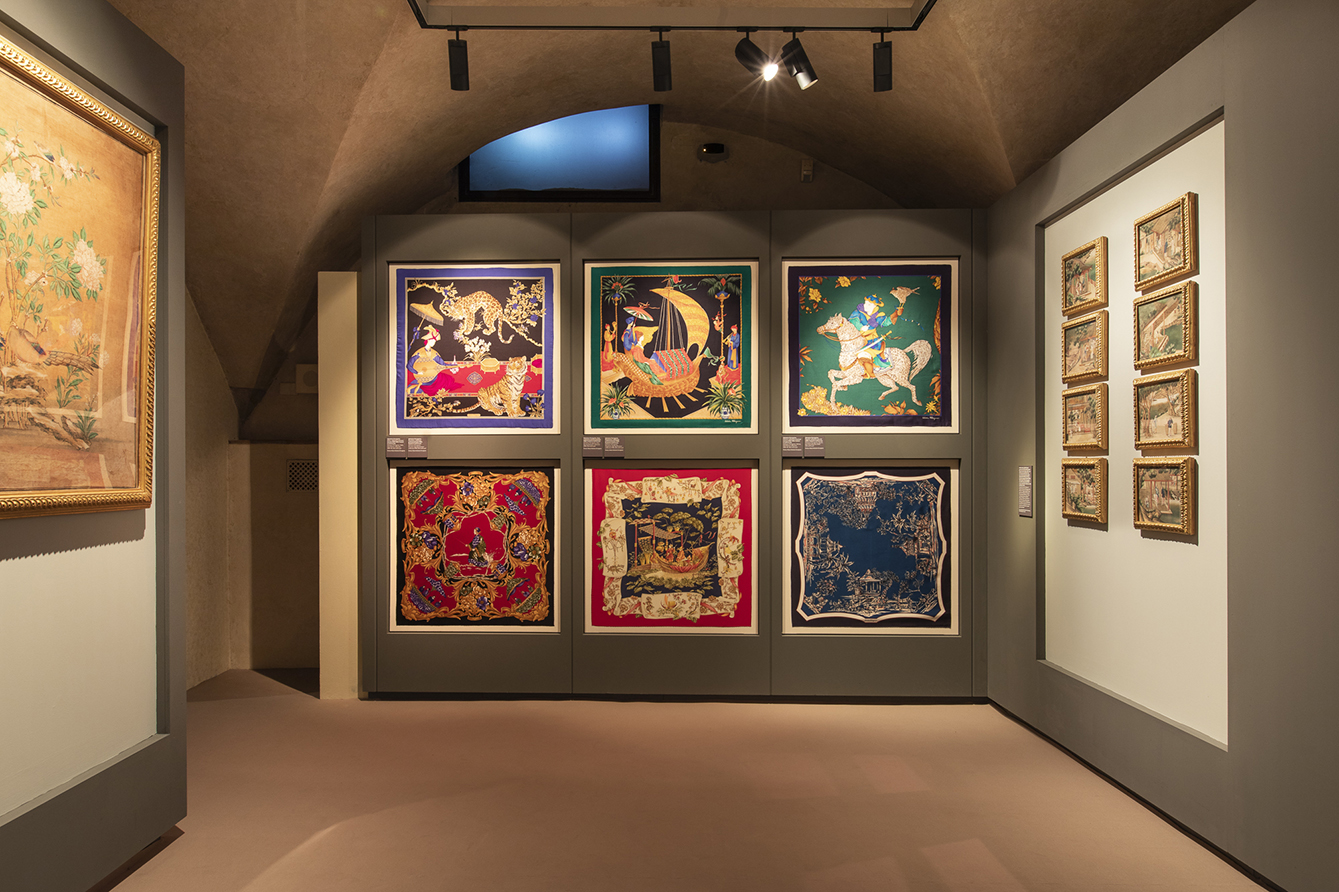 图片展示了一个艺术画廊内的一面墙，墙上挂着多幅风格各异的艺术作品，包括传统和现代元素。