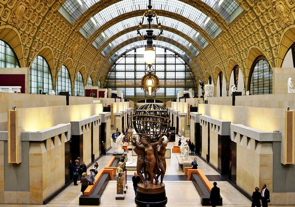这是一幅展示博物馆内部的图片，有雕塑作品，参观者，挂钟和拱形天花板，整体显得庄重而优雅。