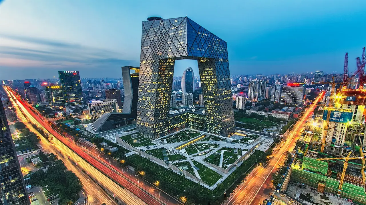 图片展示了一座现代化城市的天际线,中心是一栋独特设计的高楼,四周是繁忙的交通和闪烁的灯光。
