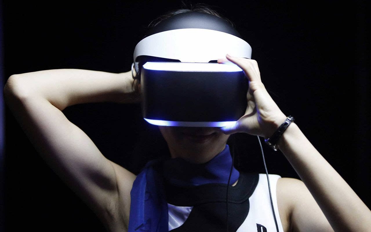 图片展示了一位女性正戴着虚拟现实头盔，头盔发出蓝光，背景为黑暗，她似乎在体验VR内容。